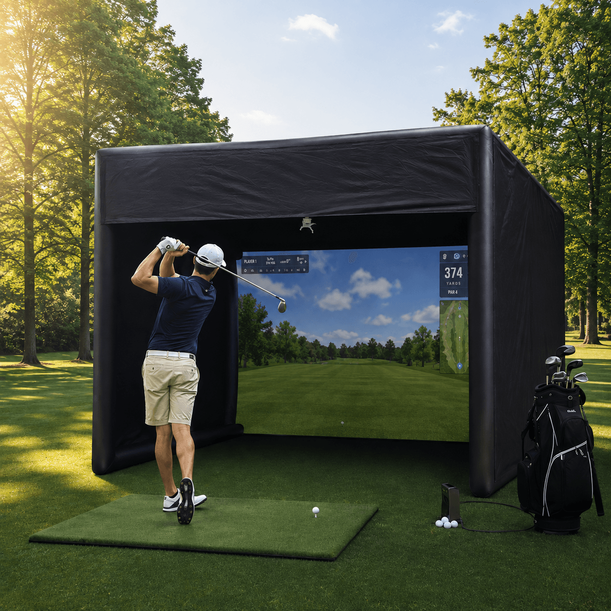 A golfer mid-follow-through inside the inflatable Woodlands Golf Sim bay, set up on grass with clubs and a launch monitor beside the mat.